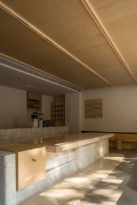 Inviting cafe interior with a large counter, dining table, and wooden chairs, set against a concrete backdrop