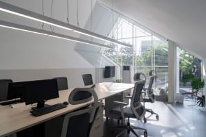 A modern office space with multiple chairs, desks, and potted plants, well lit and featuring a modern design