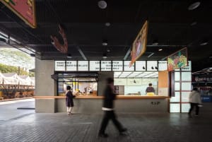 A modern restaurant scene with a counter and seating area, featuring a man in a suit walking towards the counter, with bottles and cups on display