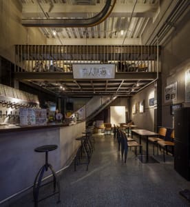 A casual restaurant with multiple dining tables and chairs, bottles on surfaces, and a warm atmosphere