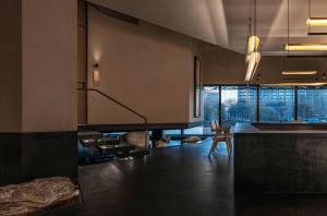 Open living area with a black tile floor, a couch, chairs, and a dining table in a contemporary and inviting atmosphere