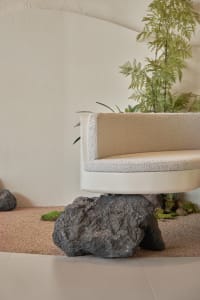A serene indoor space with a concrete bench surrounded by potted plants, creating a calming atmosphere