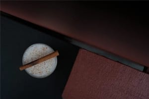 Cozy living space with a couch, table, and warm lighting, featuring a glass of milk and a cinnamon stick