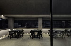 A modern restaurant interior with a large dining area featuring multiple tables and chairs, creating a clean and inviting atmosphere
