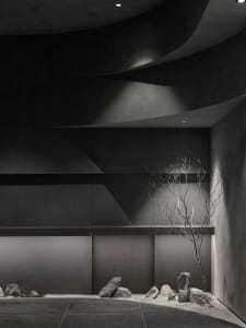 A dark room with a tree branch as its central feature, surrounded by a couch and dining table, with birds perched on the branch