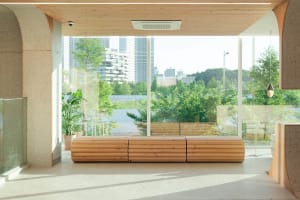 A well-lit indoor space with wooden benches and large windows allowing sunlight to enter