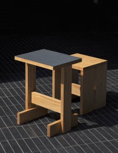A modern dining space with a wooden table and black countertop on a tiled floor, giving a clean and minimalist appearance