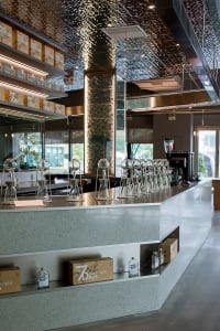 A modern restaurant counter with wine glasses, sleek surfaces, and minimalistic decorations