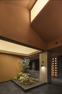 A cozy open space with a brown ceiling, featuring a bench, potted plants, and a clock on the wall