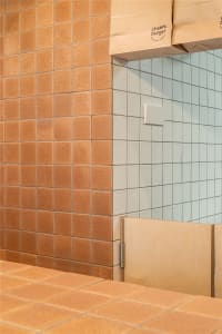 Bathroom with a brick-patterned wall, two sinks, and a bench, creating a clean and organized space with a focus on functionality and aesthetics