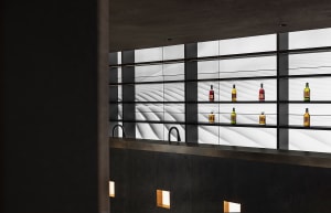 Modern bar area with marble countertop, bottles, and wine glasses, featuring a sophisticated and organized space