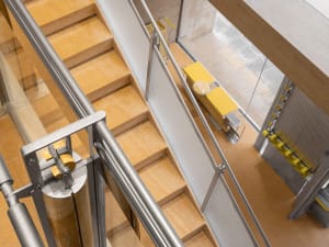 A museum interior with a wooden staircase and yellow railings, featuring multiple levels and a sense of depth