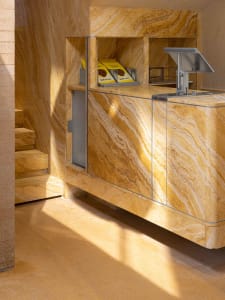 A kitchen with a marble countertop, sink, and refrigerator, featuring two cups and an elegant atmosphere due to high-quality marble materials