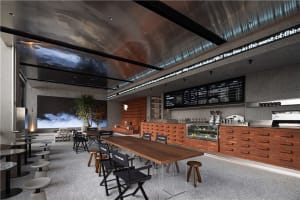 A modern restaurant interior with a large wooden table and black chairs, surrounded by ample seating options and cups on the table