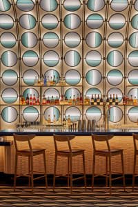 A social bar scene with a long counter, chairs, and bottles of liquor, creating a welcoming atmosphere for patrons