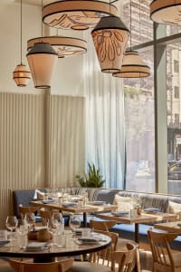 Warm and inviting restaurant interior with wooden tables, chairs, and wine glasses, creating a comfortable atmosphere for guests