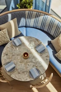A modern dining space with a marble table surrounded by chairs, cushions, and decorative items