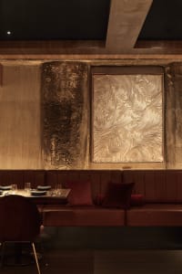 A modern restaurant interior with wooden walls, multiple tables, chairs, and couches, creating a warm and inviting atmosphere