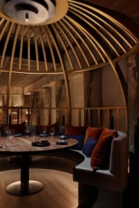 A modern dining area with a circular table, wine glasses, and couches, creating a sophisticated ambiance