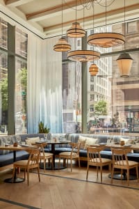 Modern restaurant interior with wood and metal elements, potted plants, and a comfortable dining atmosphere