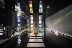 A modern interior space with a glass staircase surrounded by colorful glass panels and metal stairs