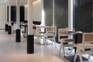 Modern restaurant interior with white tables, black and white tabletops, and minimalist chairs in a well-lit space