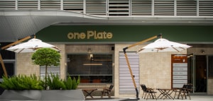 An outdoor dining area with a table and chairs, surrounded by potted plants, creating a comfortable and inviting atmosphere for customers to enjoy their meals