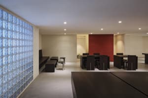 A well-lit restaurant with a red accent wall, wooden tables, and metal chairs, creating a comfortable dining area