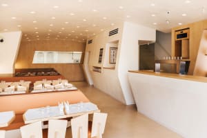 A modern restaurant dining area with white tables and chairs, clean and inviting, ready for guests