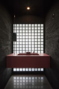 A bathroom with two sinks, one with a mirror, a toilet, and checkered-patterned walls, set in a well-lit and inviting space