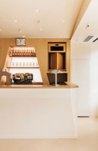 Warm and inviting restaurant kitchen with wooden walls and floors, featuring two sinks, bottles, and a clock, creating a cozy atmosphere
