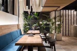 A warm and inviting dining area with wooden tables and chairs, surrounded by potted plants