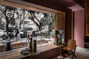 Cozy restaurant interior with wooden floors and walls, dining tables, potted plants, and decorative vases