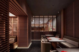 Warm and inviting restaurant interior with wooden walls and tables, featuring orange placemats and comfortable seating