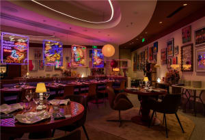 Elegant dining space with seating areas, tables, artwork, and warm lighting