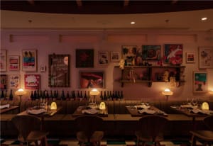 Cozy dining area with wooden tables, chairs, and wine bottles, set in a warm and inviting atmosphere