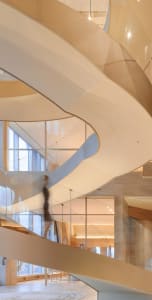 A grand staircase with wooden steps and a metal railing, set against a rendered background, suggesting a sense of grandeur and elegance