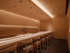 A modern restaurant with wooden floors and walls, featuring dining tables and chairs in a welcoming atmosphere