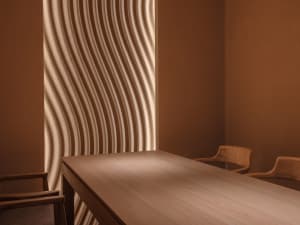 A cozy dining area with a wooden table and chairs, surrounded by warm natural materials and sunlight