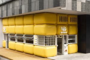 A warm and inviting Asian restaurant with yellow walls, yellow exterior, and large yellow balls on the outside wall, featuring dining tables and chairs inside