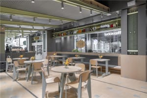 A coffee shop interior with a bar and tables, featuring numerous bottles and a welcoming atmosphere