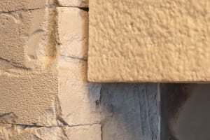 A traditional building exterior featuring a stone wall with a brick pattern, warm lighting highlighting the textures and details of the stone and brick