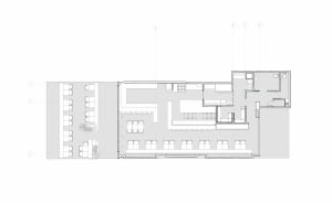 2D floor plan of a modern commercial building with concrete and glass materials, featuring various rooms and spaces, including a central atrium and offices