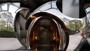 Elegant hotel lobby entrance with glass doors, metal frame, and chandeliers providing illumination