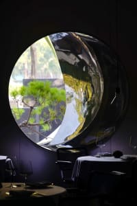 Elegant dining space with a round table, chairs, potted plants, and a clock on the wall, set in a restaurant-like atmosphere
