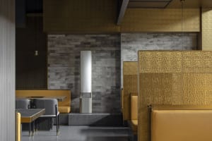 Empty restaurant interior with yellow walls, two dining tables, and a bench, creating a cozy atmosphere for dining and socializing