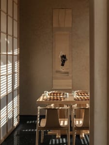 A dining area with a wooden table and chairs, set with cups, in a calm and inviting atmosphere
