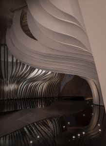 A large, modern interior space with curved walls, reflective surfaces, and a minimalist atmosphere, featuring clean lines and sleek surfaces, with ample open area and dim lighting