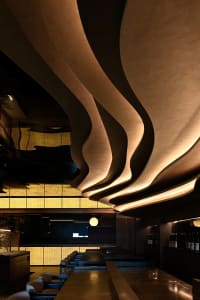 Elegant hotel lobby with a curved wooden wall, bottles, and two chairs, featuring a sophisticated atmosphere and attention to both aesthetics and functionality