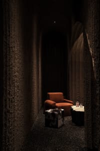 Cozy living space with an orange chair, a table with a bottle, and rock wallpaper on the walls